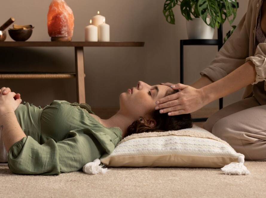 A close up picture of an employee giving head massage to women lying on bed