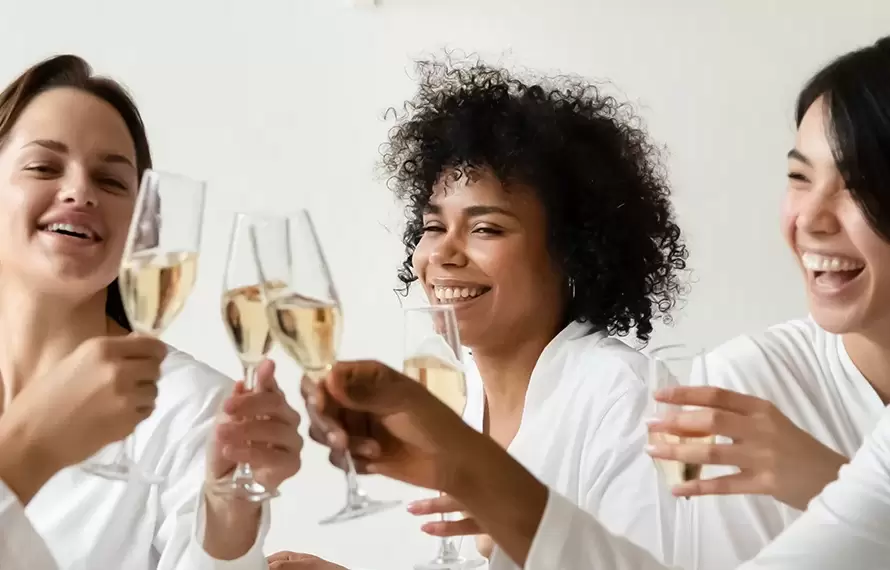 Several women lounging and talking on yoga mats in a lush, green garden setting during a day retreat.