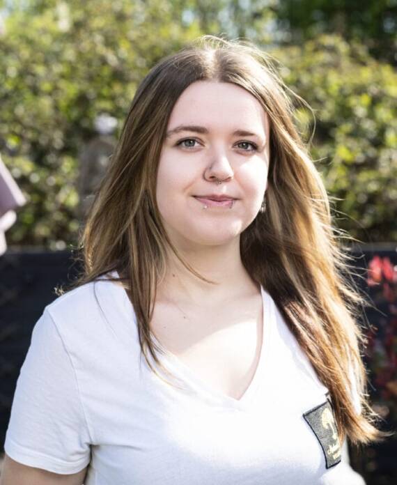 A professional spa therapist dressed in a white uniform standing in a serene treatment room, ready to provide expert wellness and massage services
