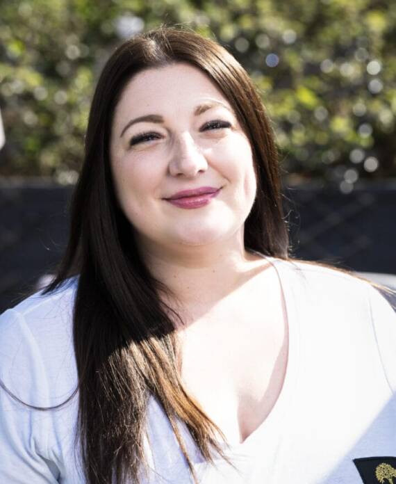 A professional spa therapist dressed in a white uniform standing in a serene treatment room, ready to provide expert wellness and massage services