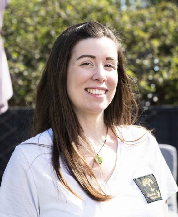 A professional spa therapist dressed in a white uniform standing in a serene treatment room, ready to provide expert wellness and massage services