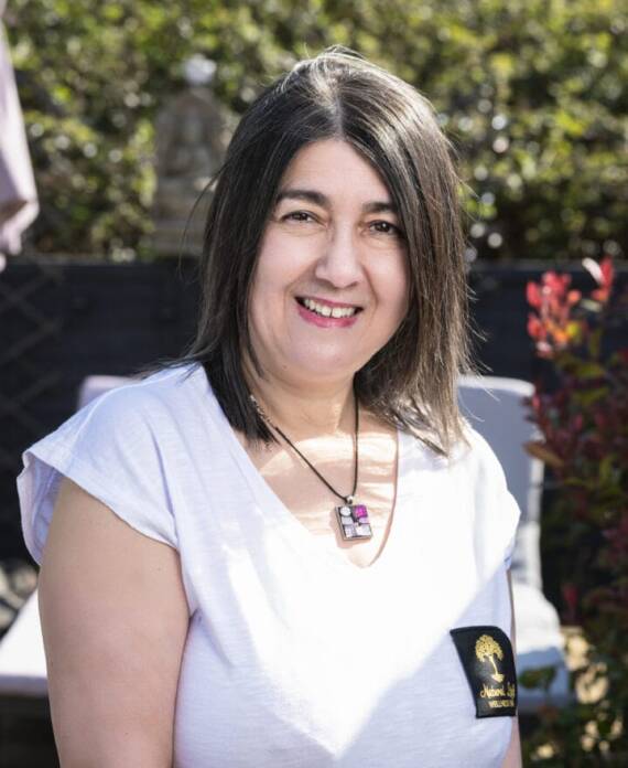A professional spa therapist dressed in a white uniform standing in a serene treatment room, ready to provide expert wellness and massage services